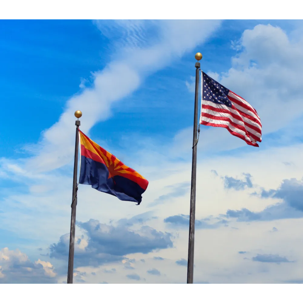  U.S. and Arizona flag on poles blowing in the wind with a blue sky